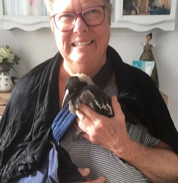 woman with her arm in a sling, cradling magpie