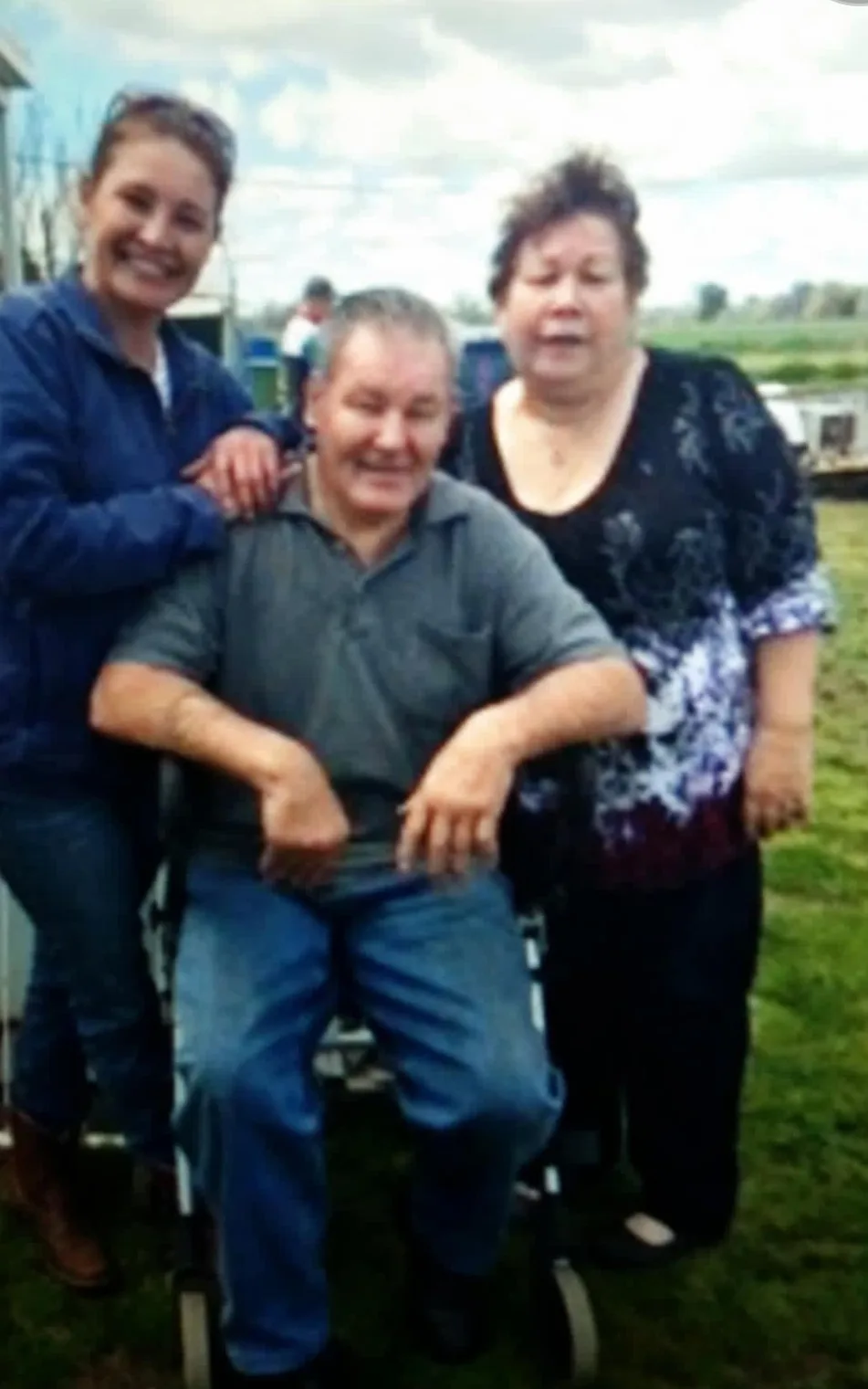 man in wheelchair sitting , woman in black standing and another woman in black standing