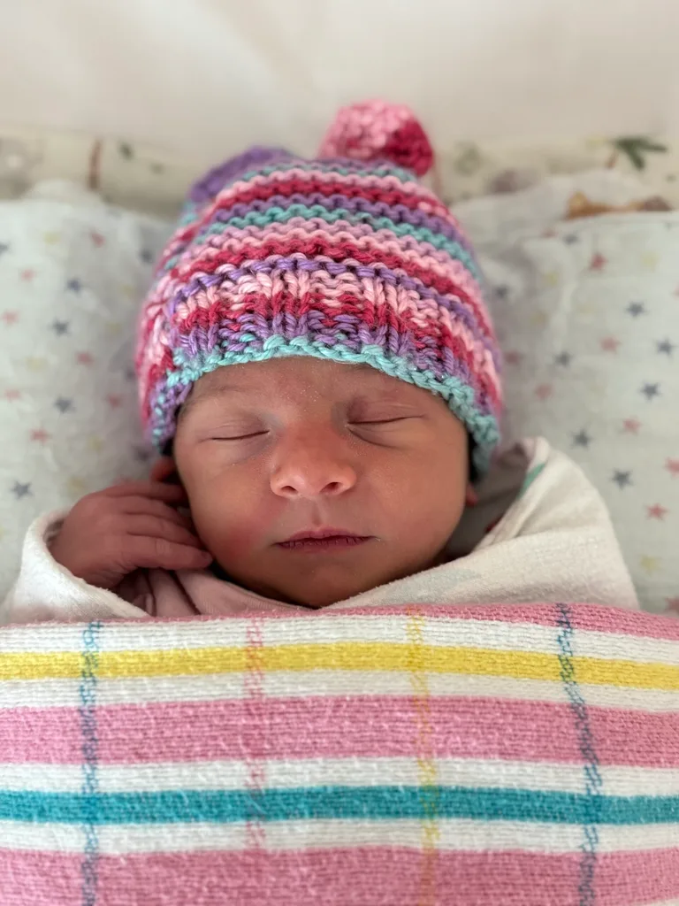 Image of newborn baby wearing knitted beanie and hospital blanket