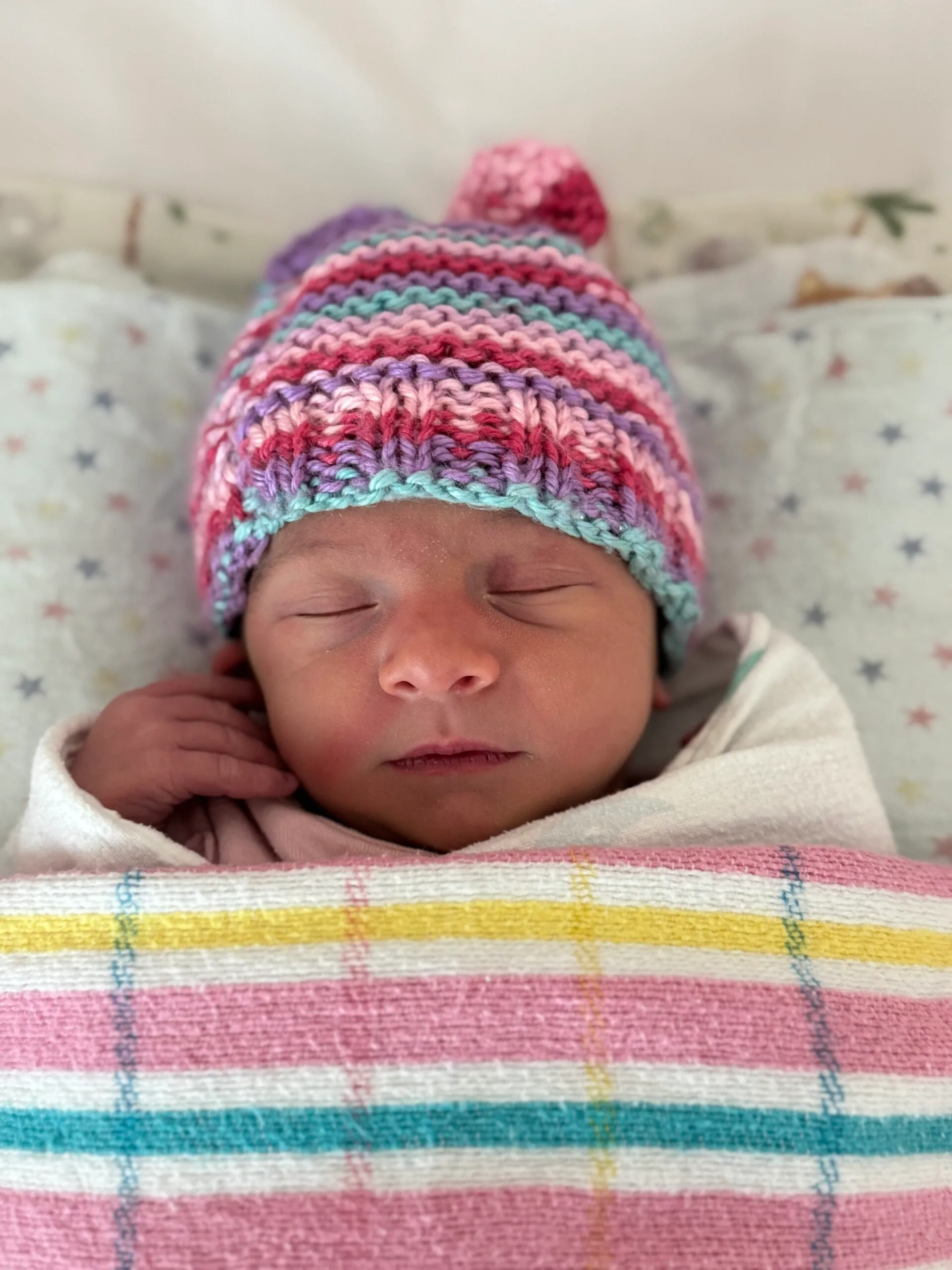 Image of newborn baby wearing knitted beanie and hospital blanket