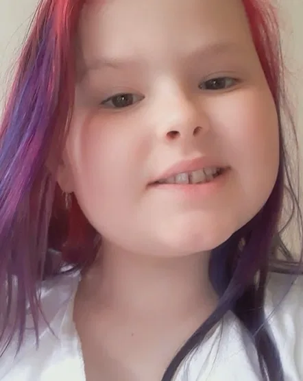 Little girl with red hair smiling at camera.