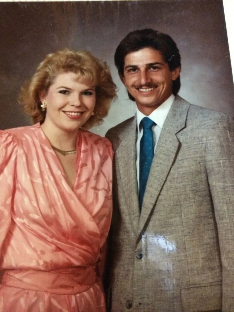 Vintage picture of woman wearing peach coloured dress and man wearing brown suit smiling,.