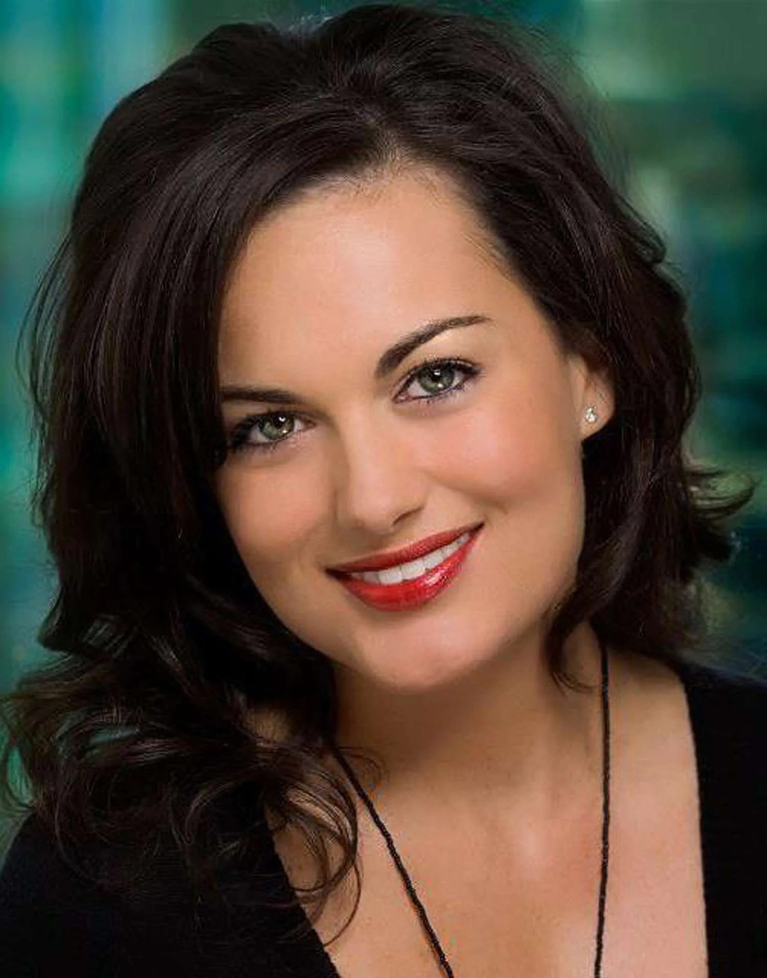a woman with dark hair, green eyes and red lipstick smiling at the camera