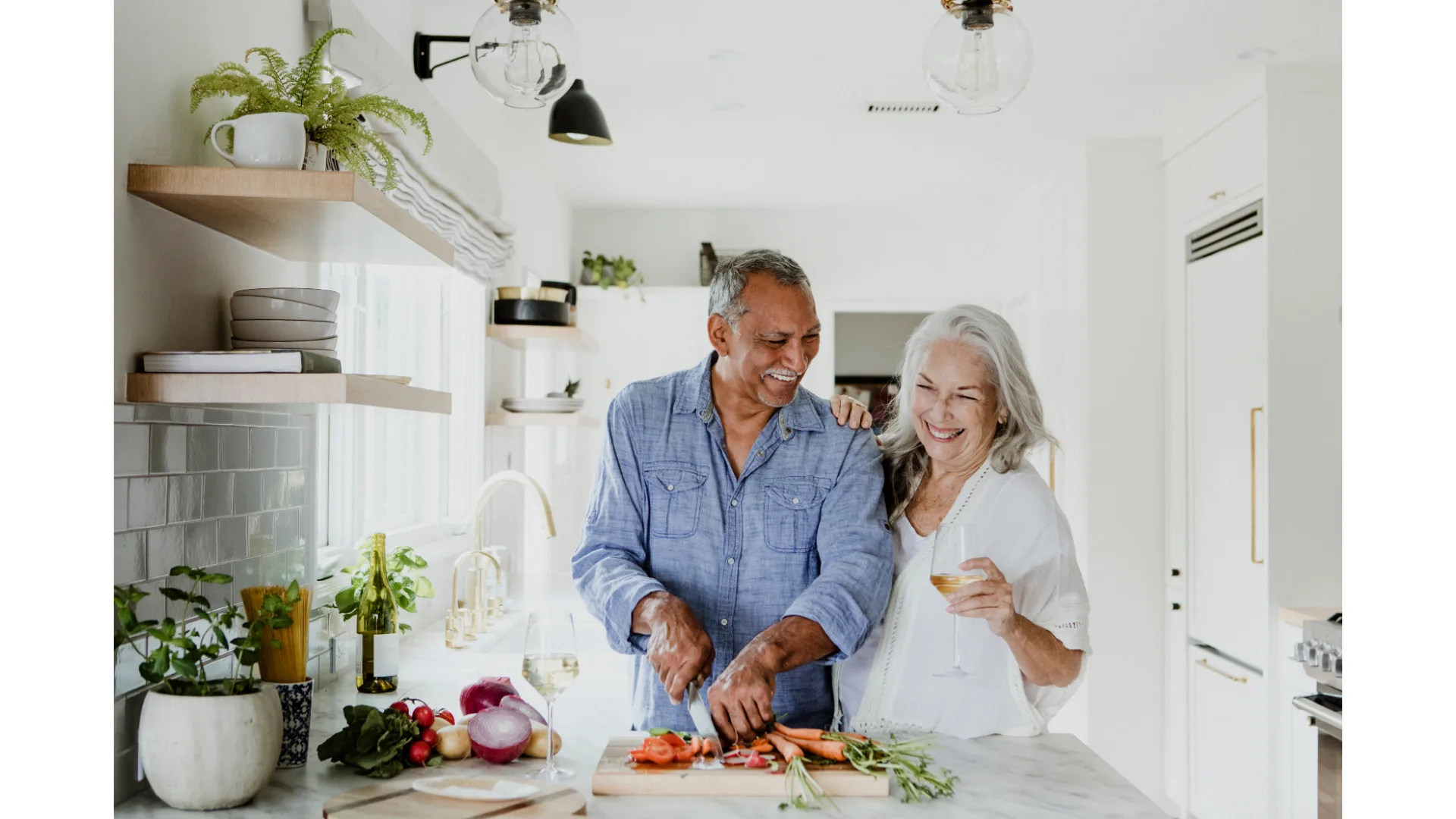 An older couple preps vegetables in their kitchen.