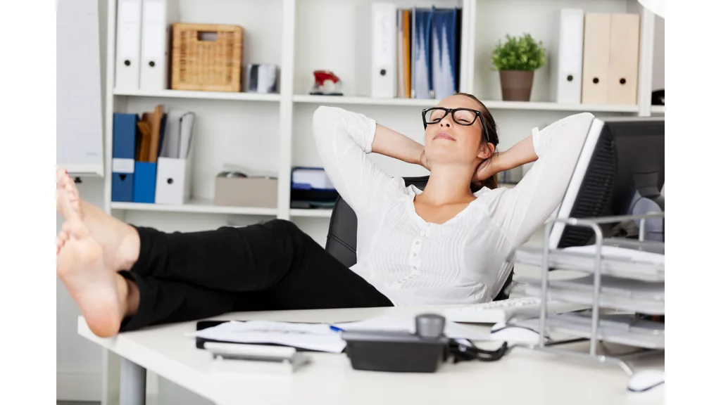 A woman enjoys an afternoon nap at her desk.
