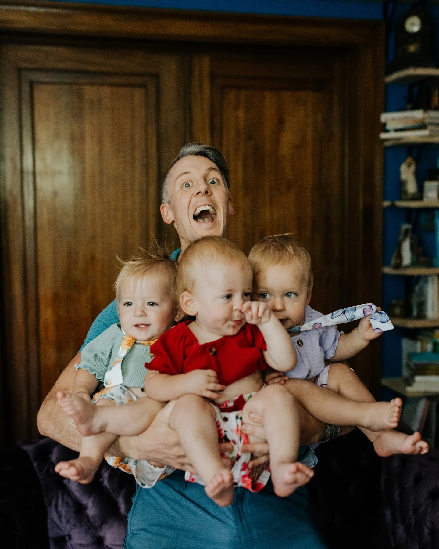 one man has his arms full with three toddlers