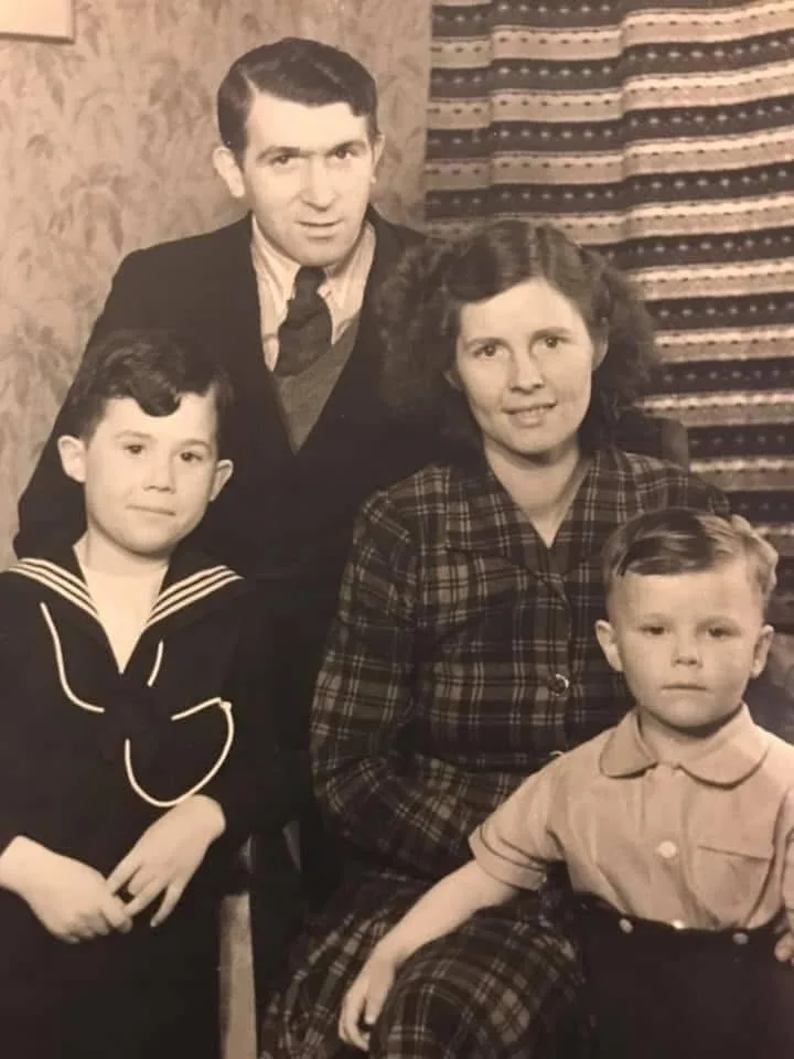 An old black and white photo of a mum and dd with two children