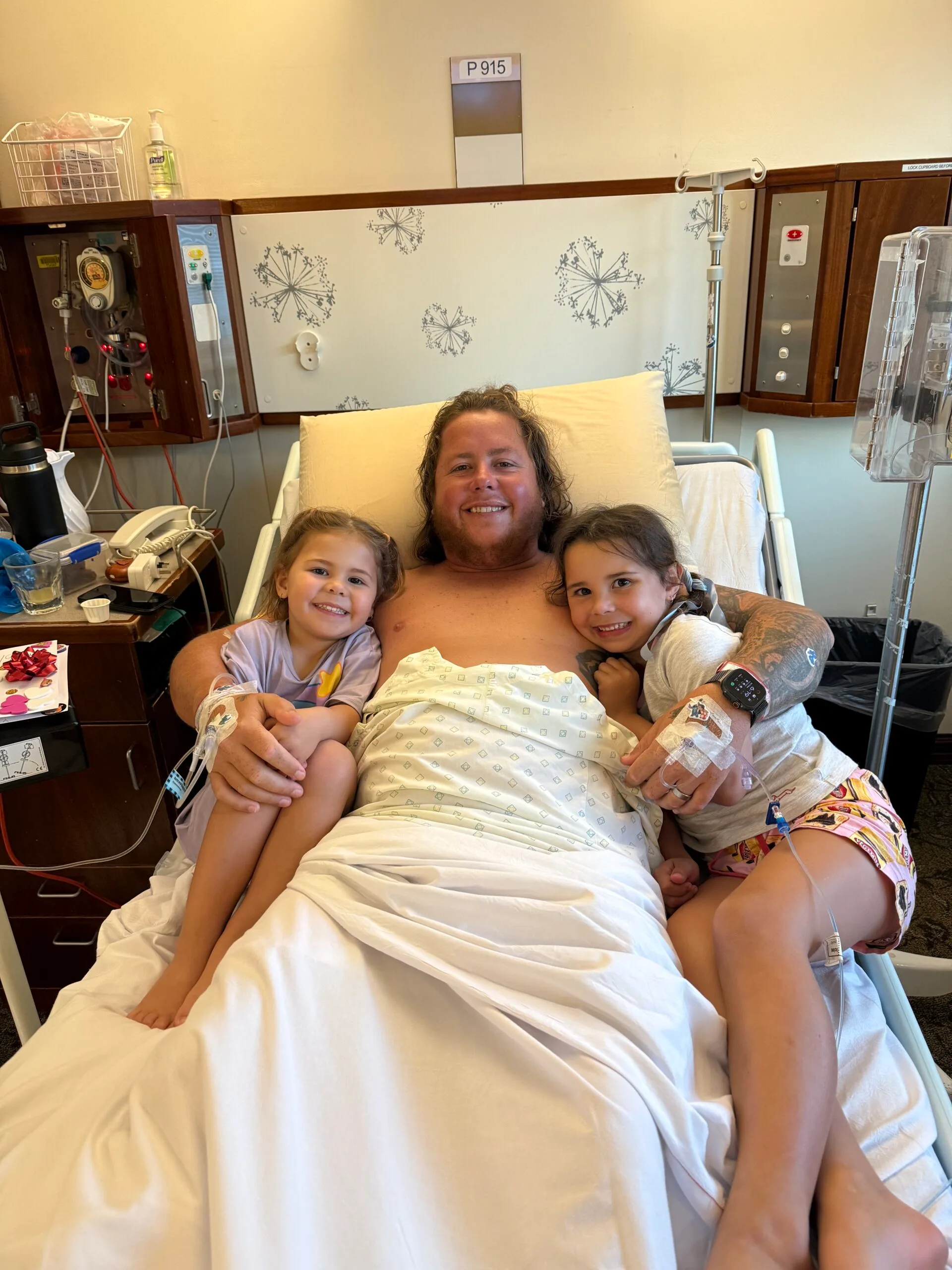 a man in hospital bed with two daughters