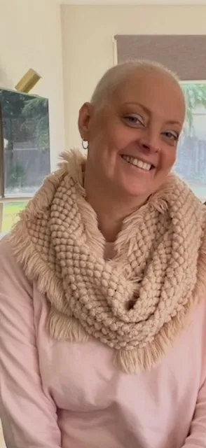 Nicole smiling with bald head and scarf around neck