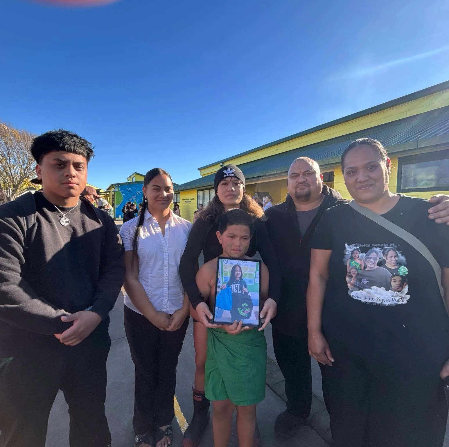 family wearing black holding a photo of daughter