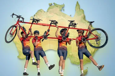 The four women with Ruby the quad tandem bike. In the background is a map of Australia.