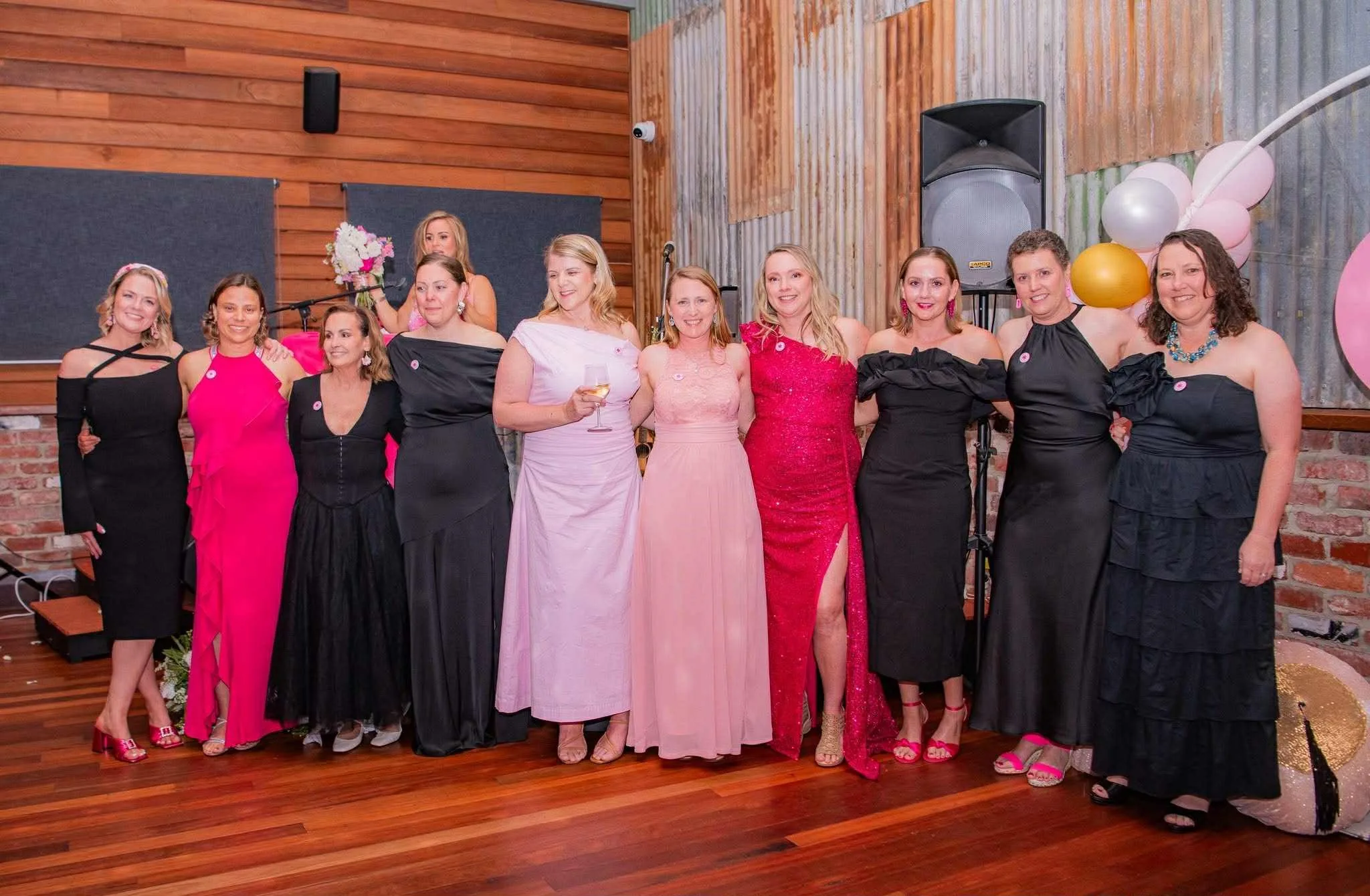 Women in line in evening dresses in white pink and black at the Big Boobie Ball in 2025