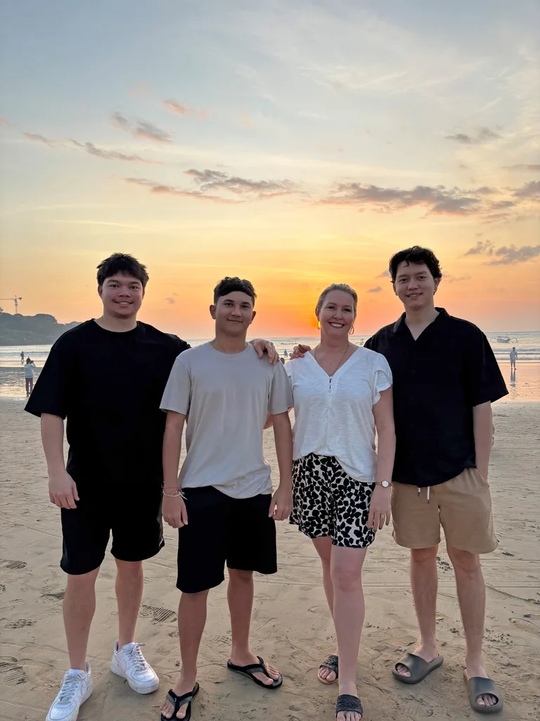 Image of mother three sons at sunset on beach
