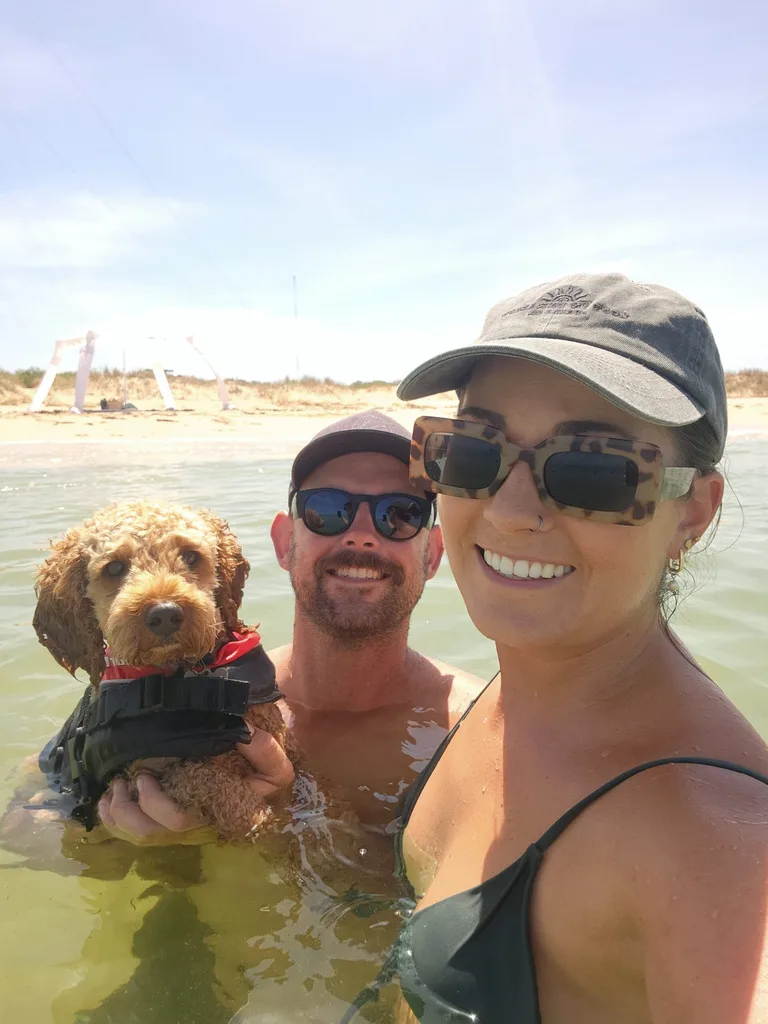 Dog, man and woman in the water at a beach
