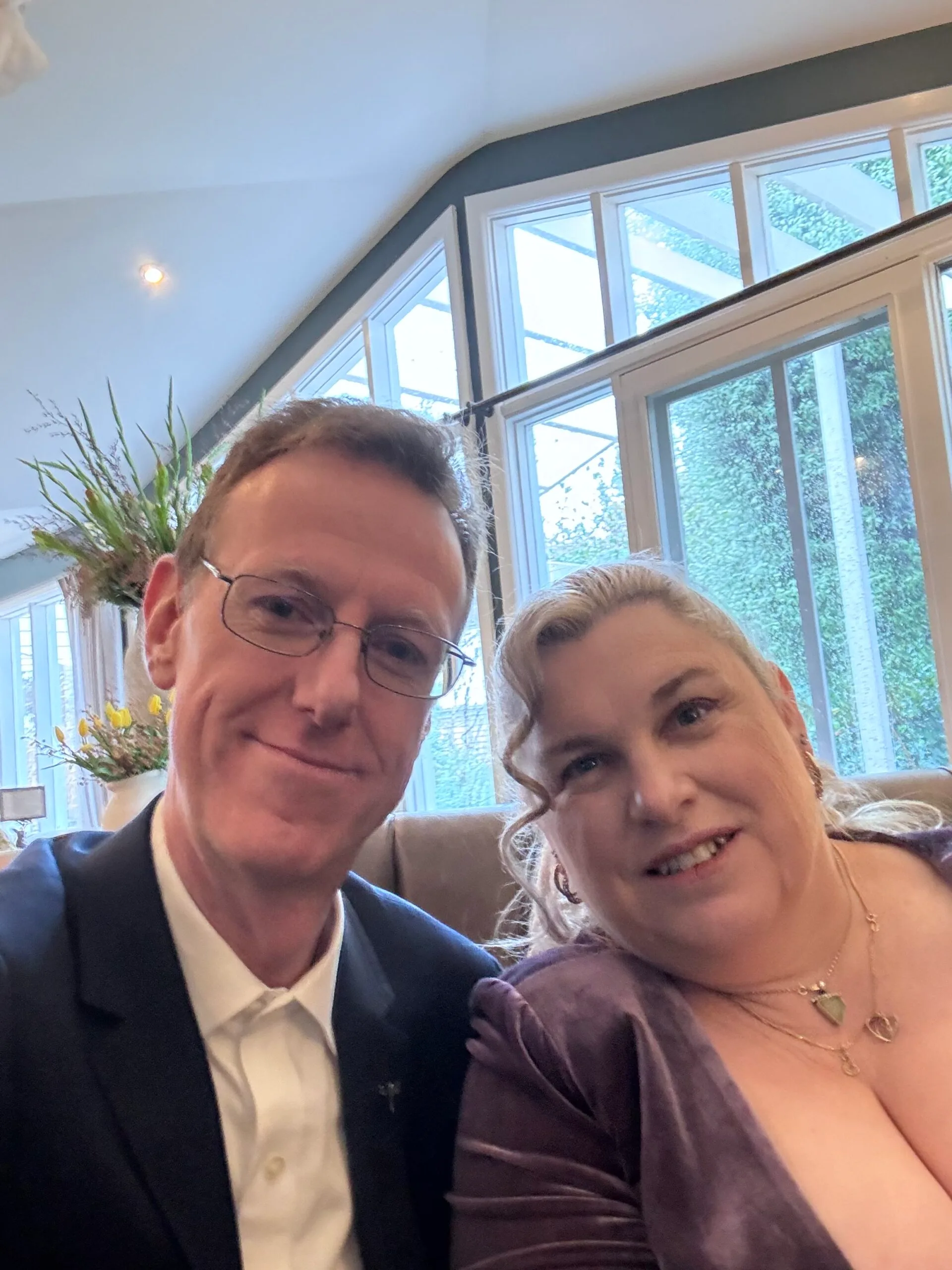 Left: Man with glasses, wearing black suit smiling at camera. 

Right: Woman with blonde hair, wearing purple dress smiling at camera.