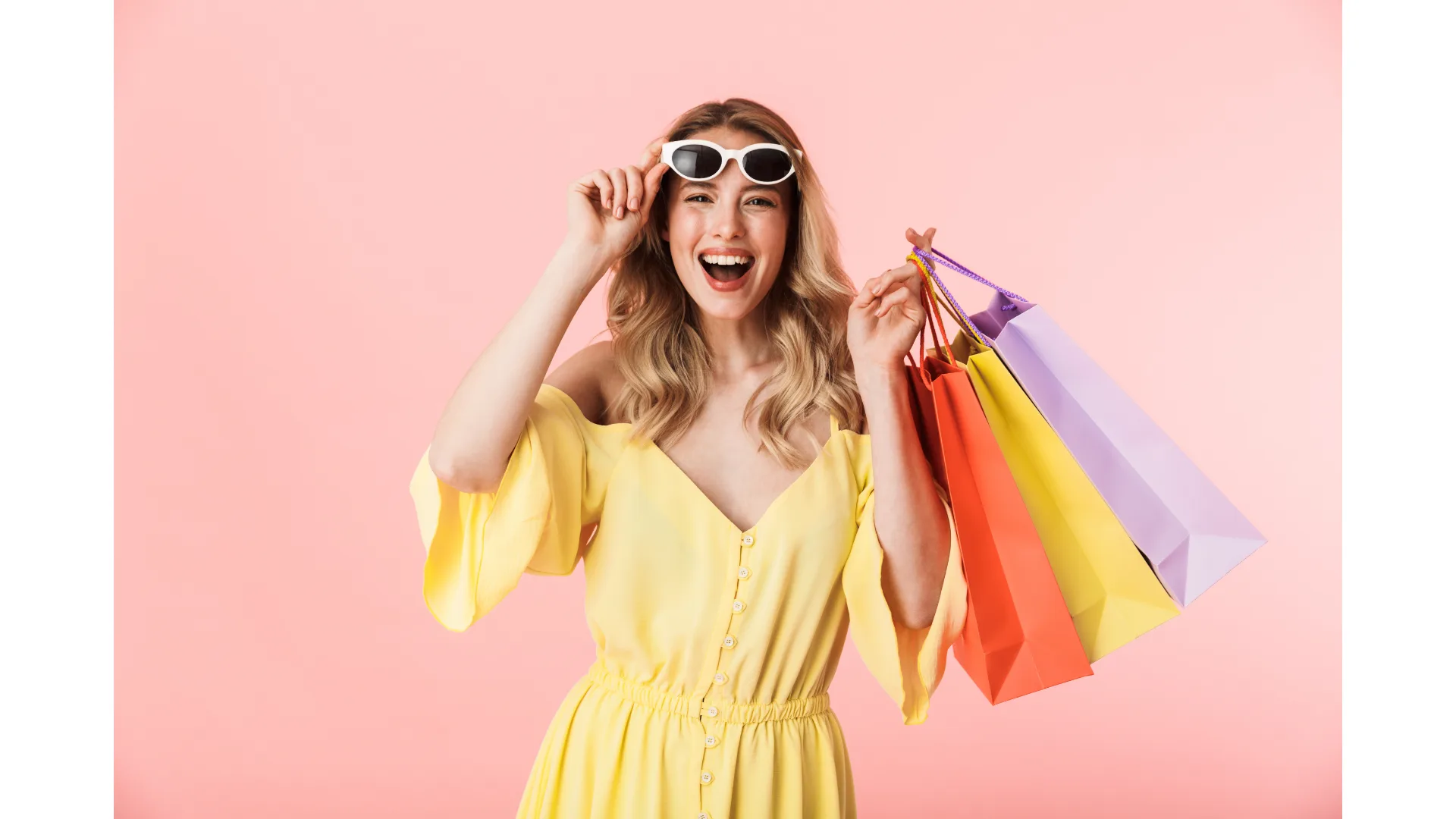 A woman in a yellow dress holds shopping bags.