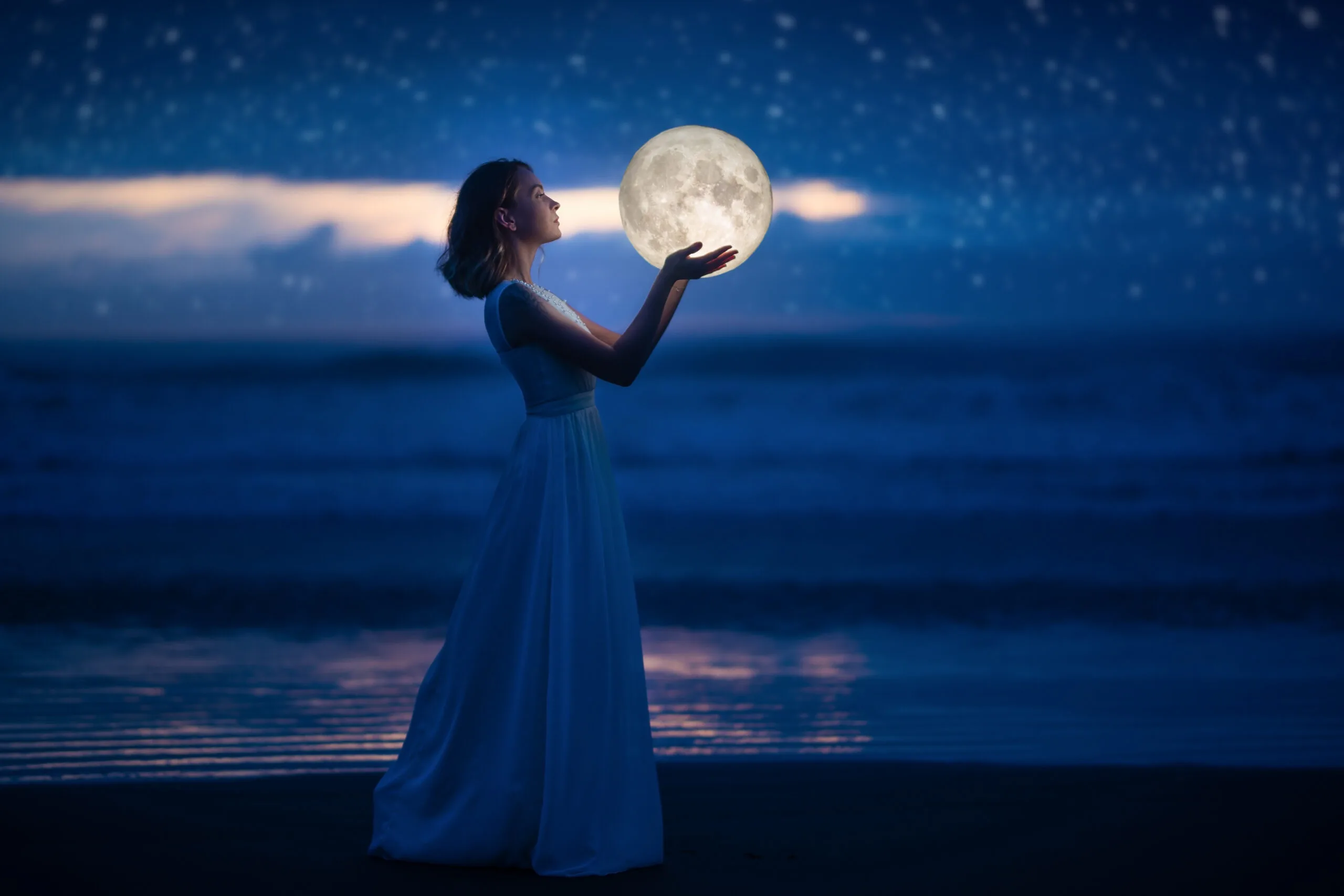 A young girl on a night beach holds the moon, with a starry sky. Art photography
