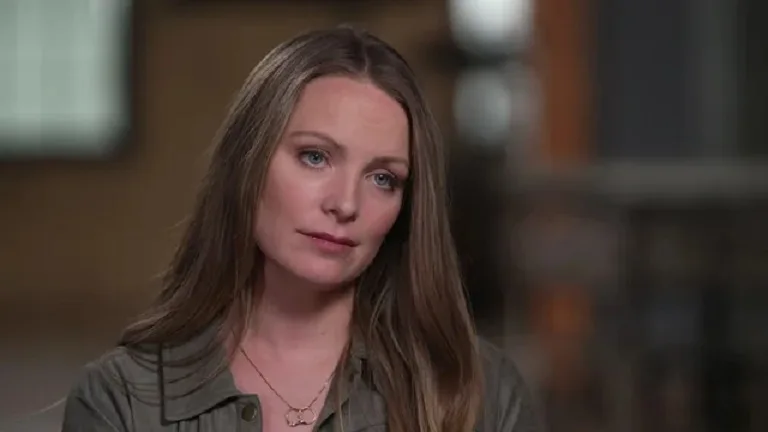 Woman, Nicole Lenway, with brown hair and blue eyes wearing green shirt looking into camera with distressed stare.