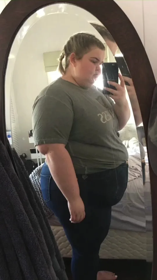 girl in t-shirt and jeans taking photo in the mirror