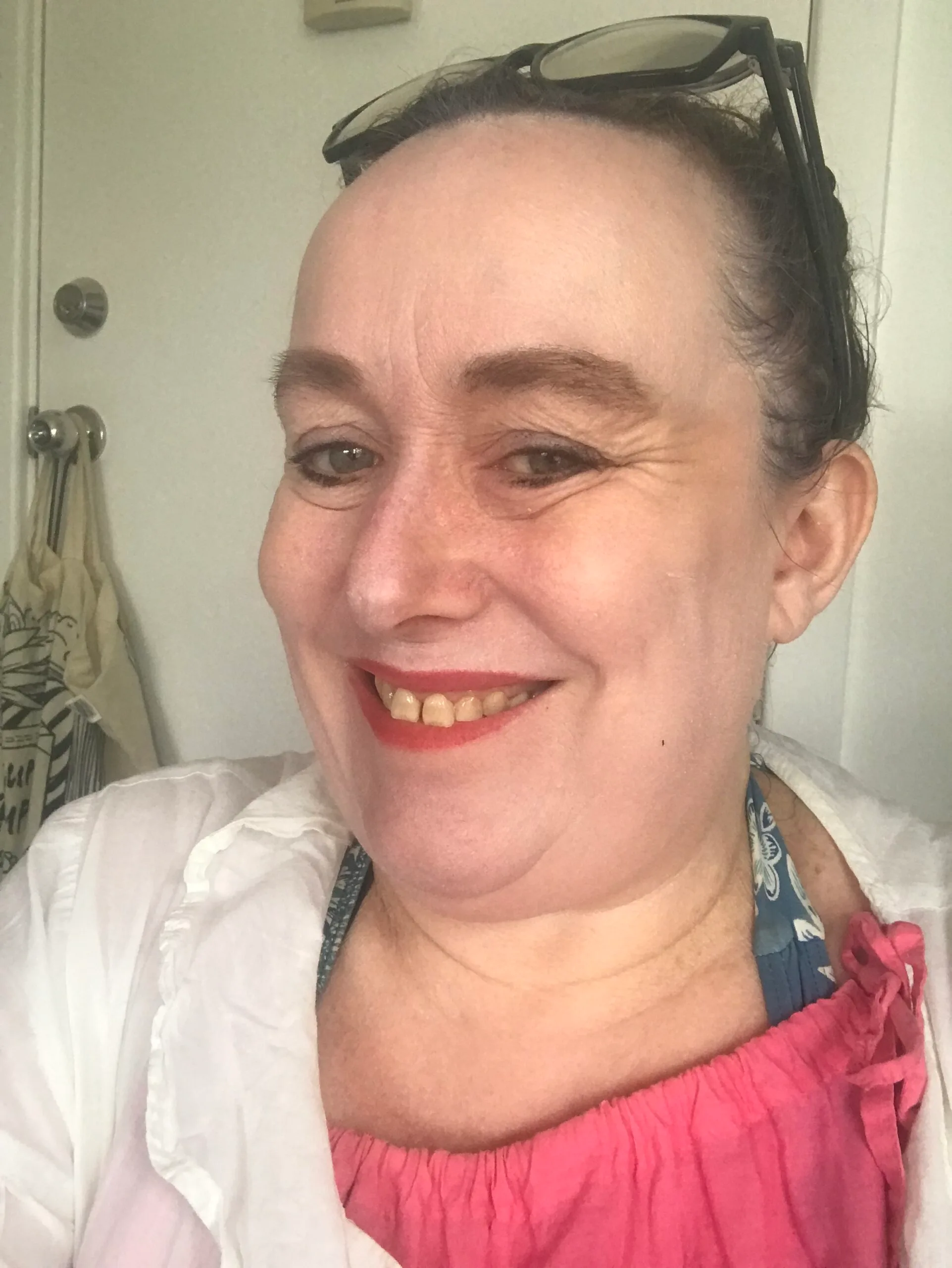 woman in red lipstick pink shirt smiling in selfie