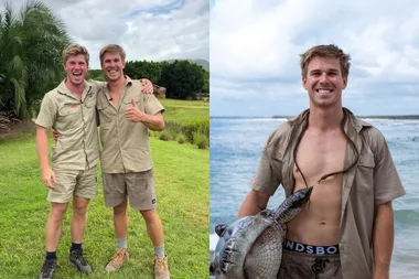 Two men in khaki standing on grass and man holding inflatable croc wearing khaki shirt with plastic snake