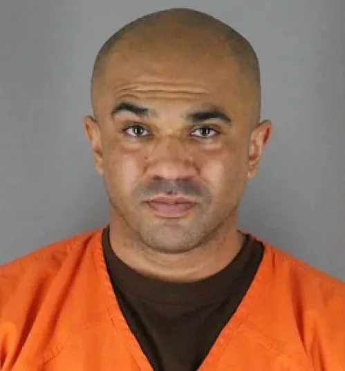 Man wearing orange prison uniform. raising left eyebrow while staring at camera.