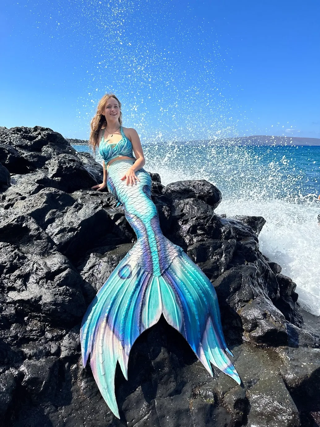 Image of woman laying on a rock wearing a mermaid tail