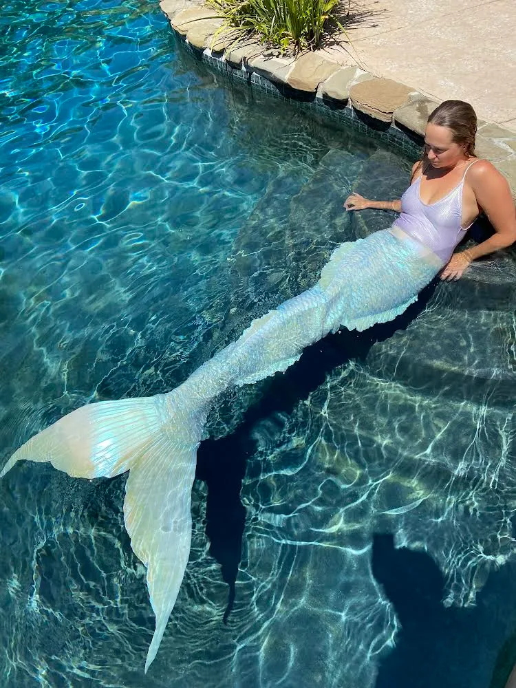 Image of woman laying in pool wearing mermaid tail