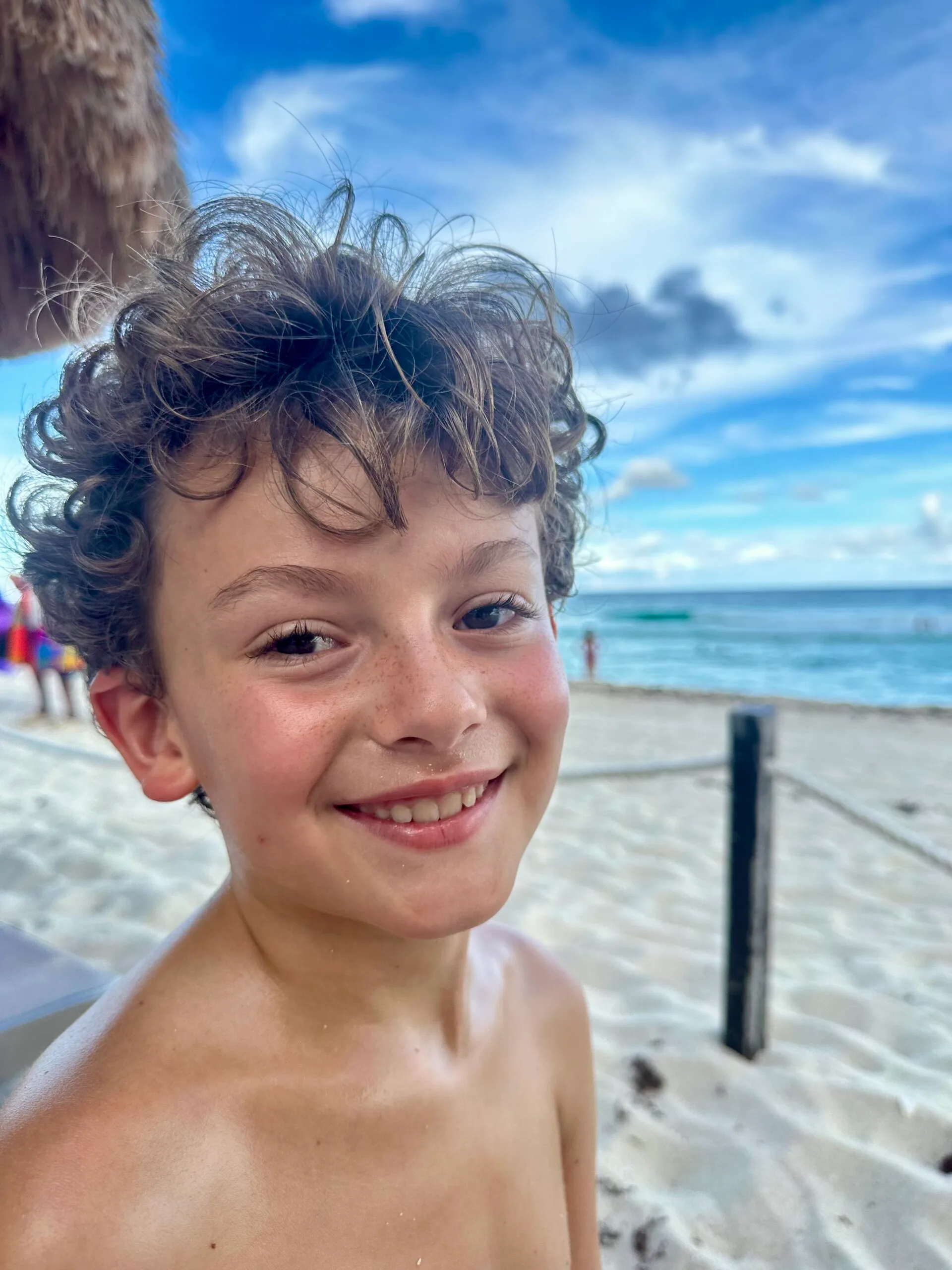 young boy smiling for the camera on beach 