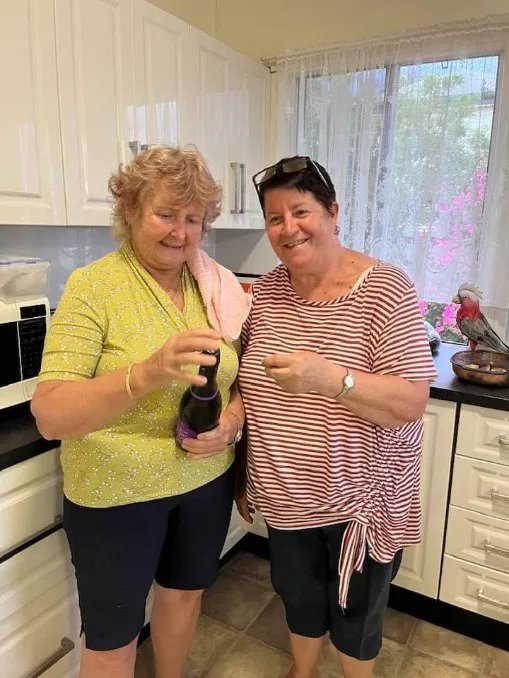 two women in a kitchen opening wine bottle