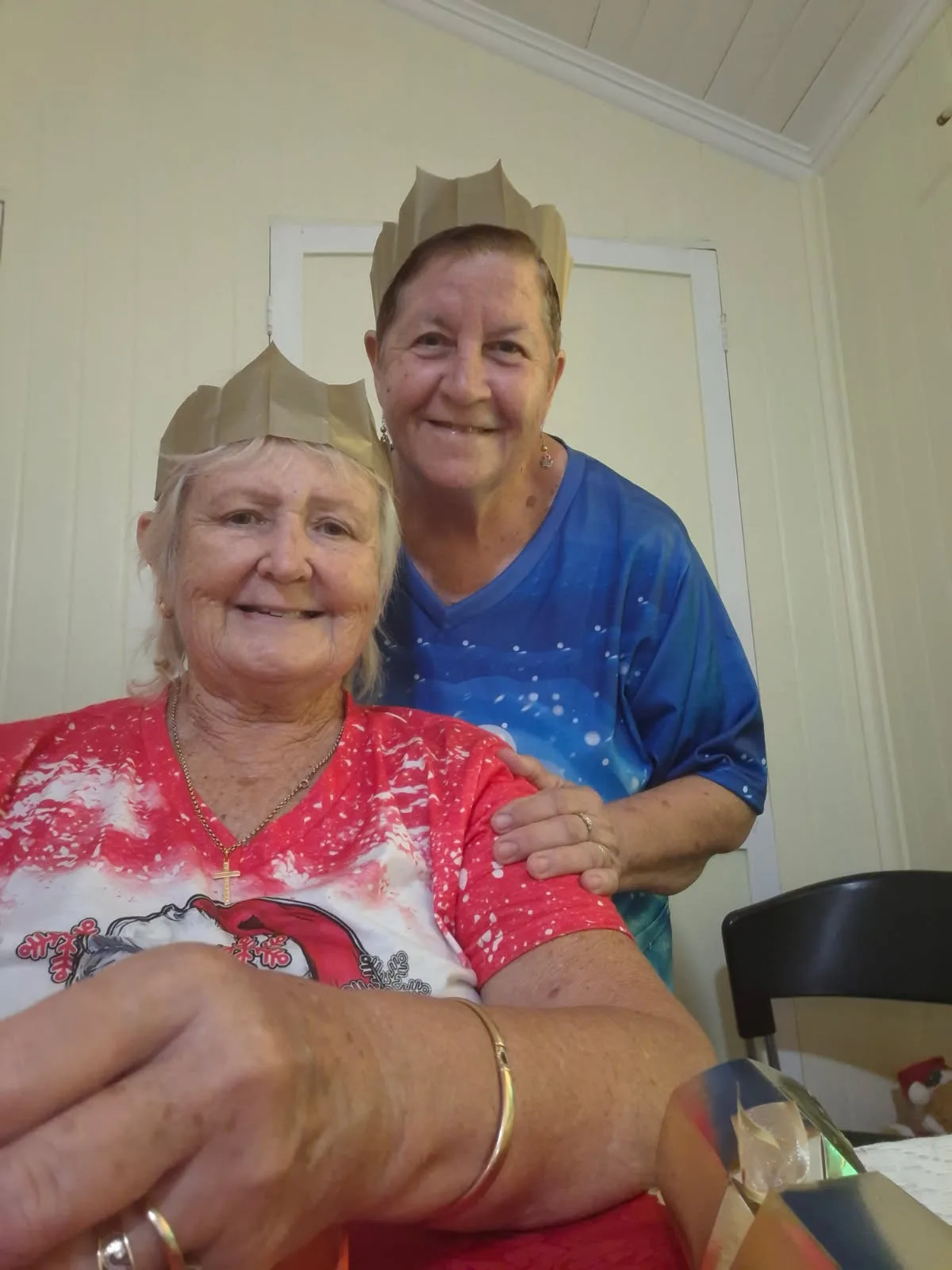 two women wearing paper Christmas hats