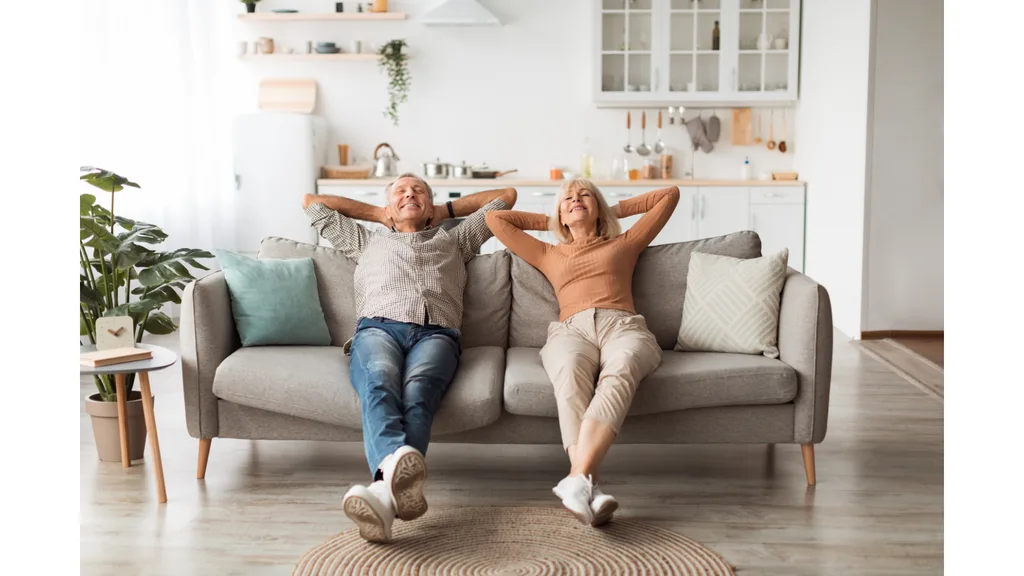 An older couple looks relaxed as they recline on a couch.