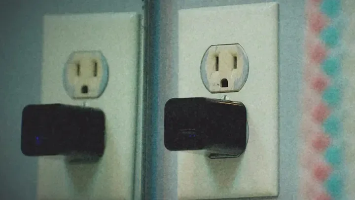 Black charger with a blue light plugged into a socket.
