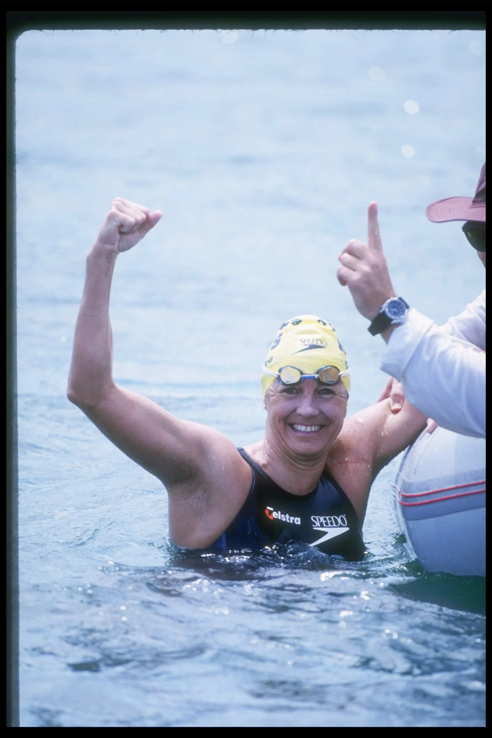 shelley in ocean swimming cap on and arm in the air