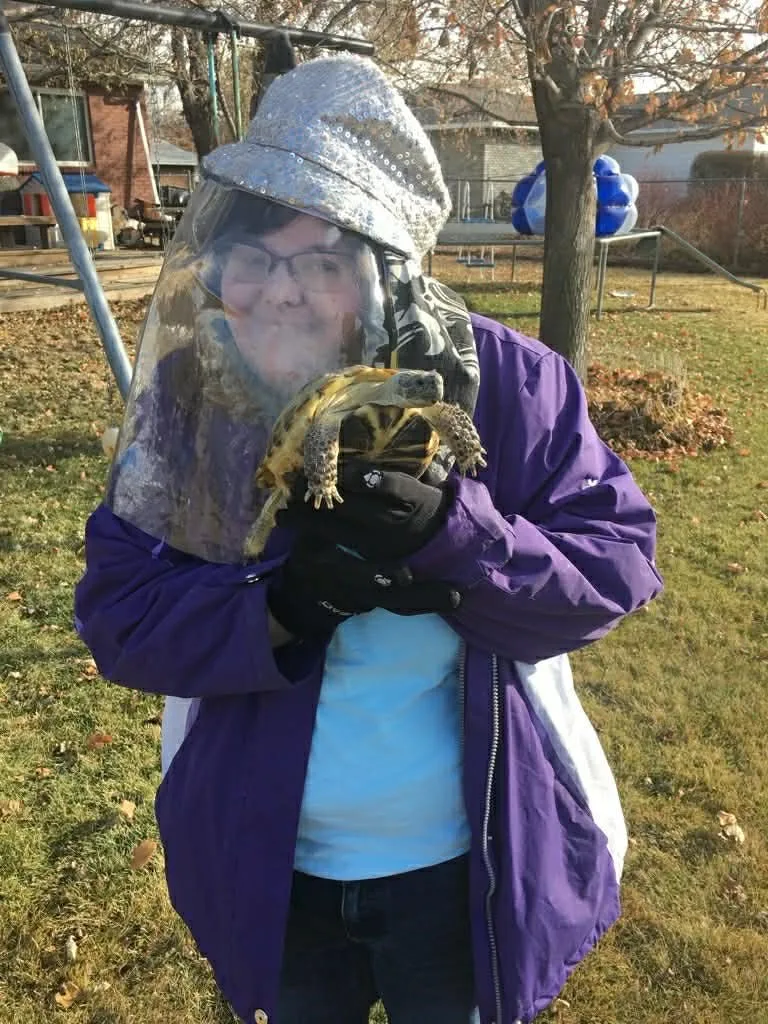 woman in PPE holding turtle