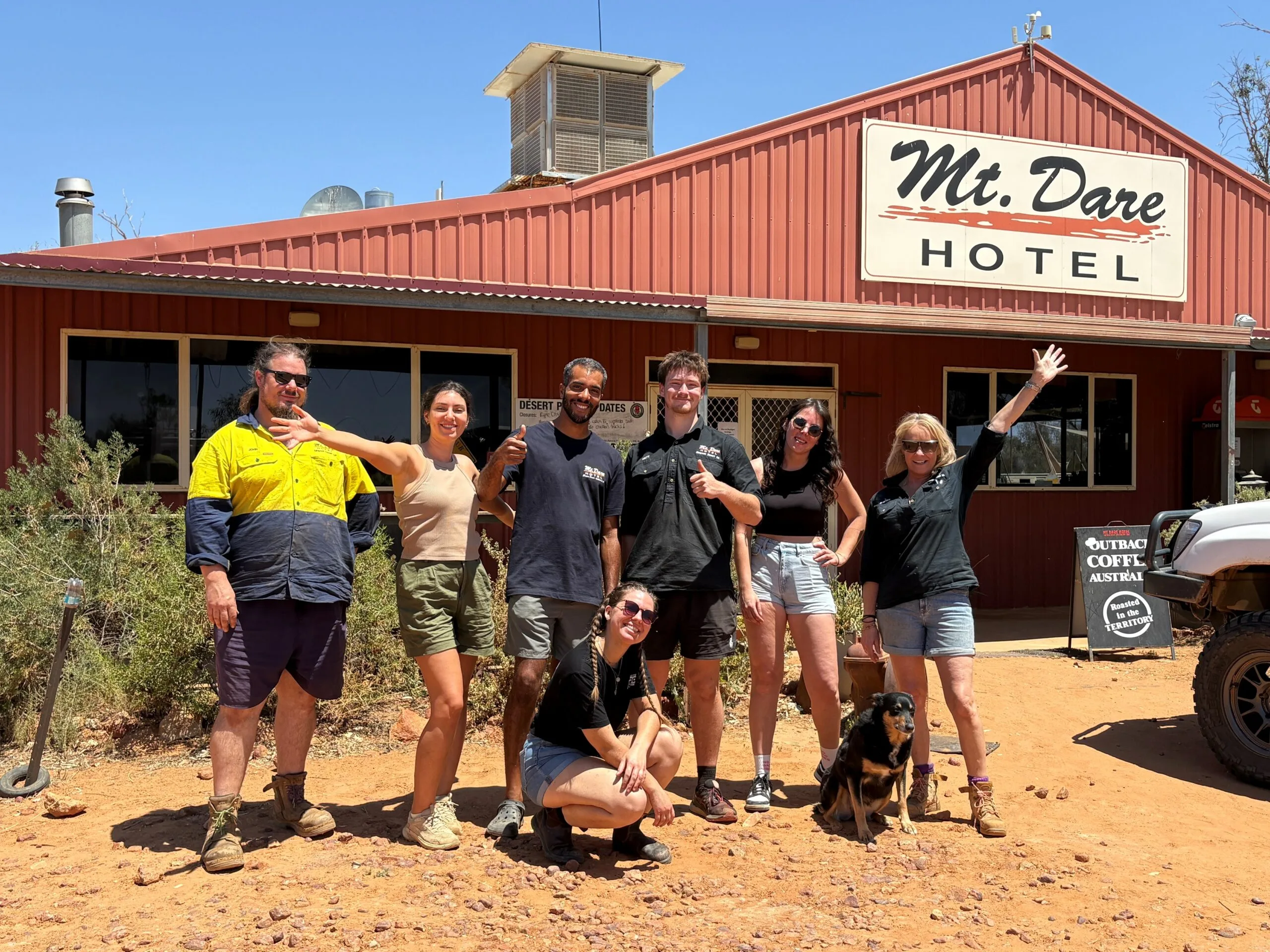 A group of people standing in front of the Australian outback pub Mt Dare Hotel