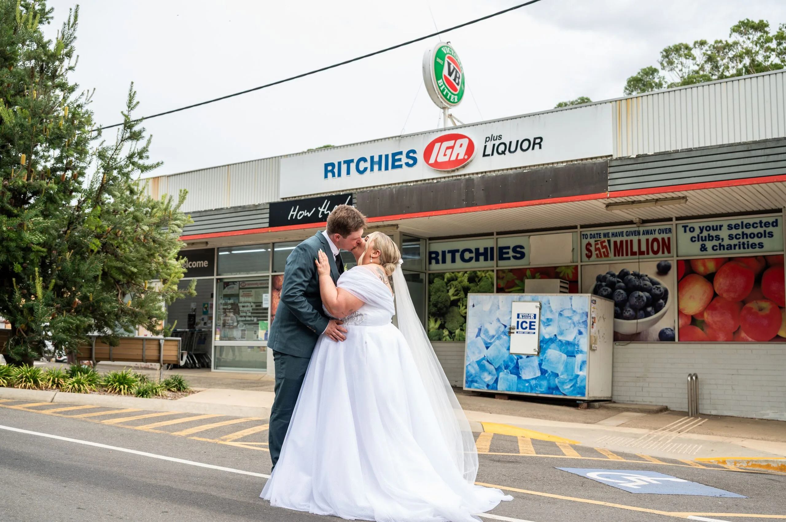bride and groom kiss in front of supermarket