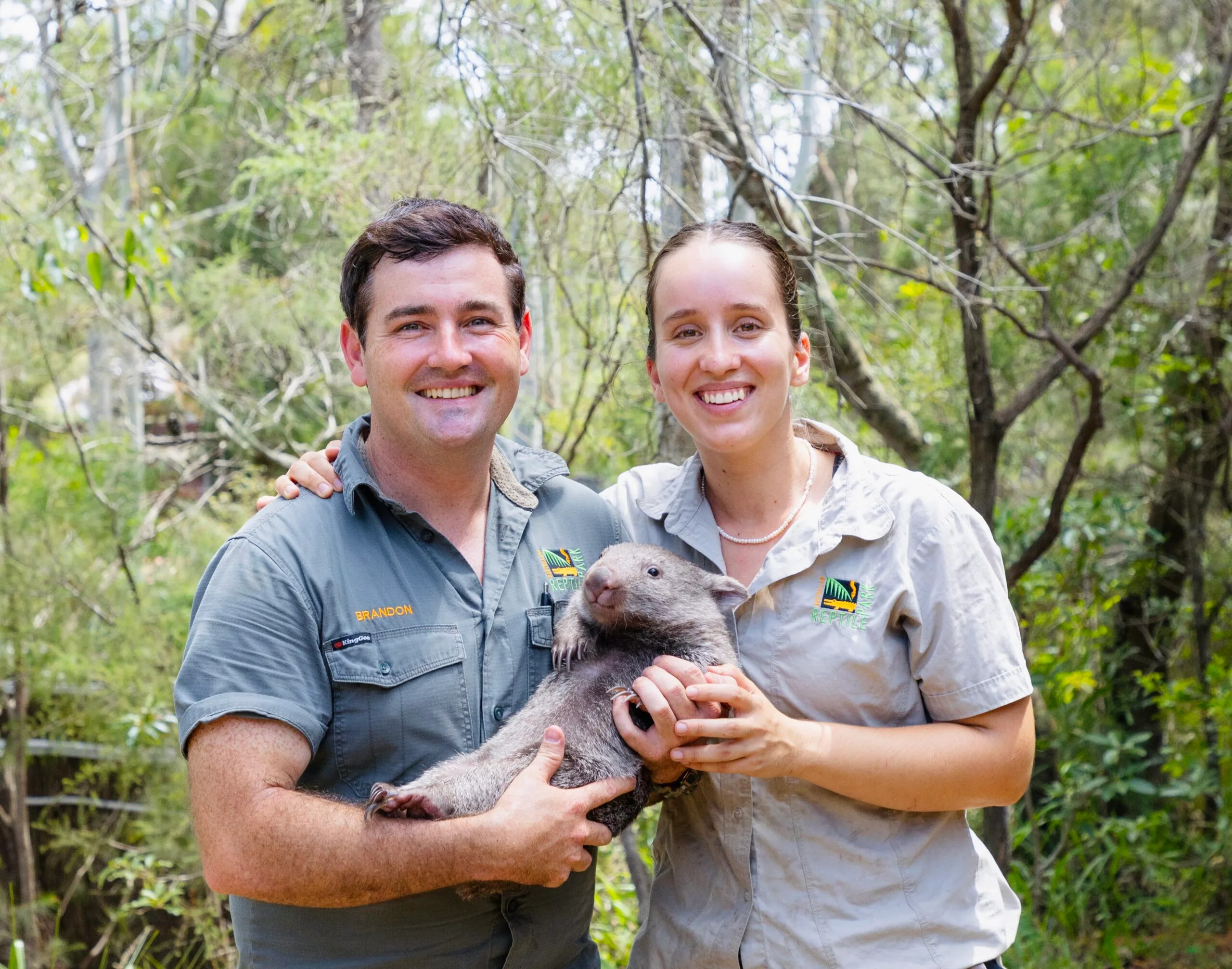 Image of zoo keepers holding wombat joey
