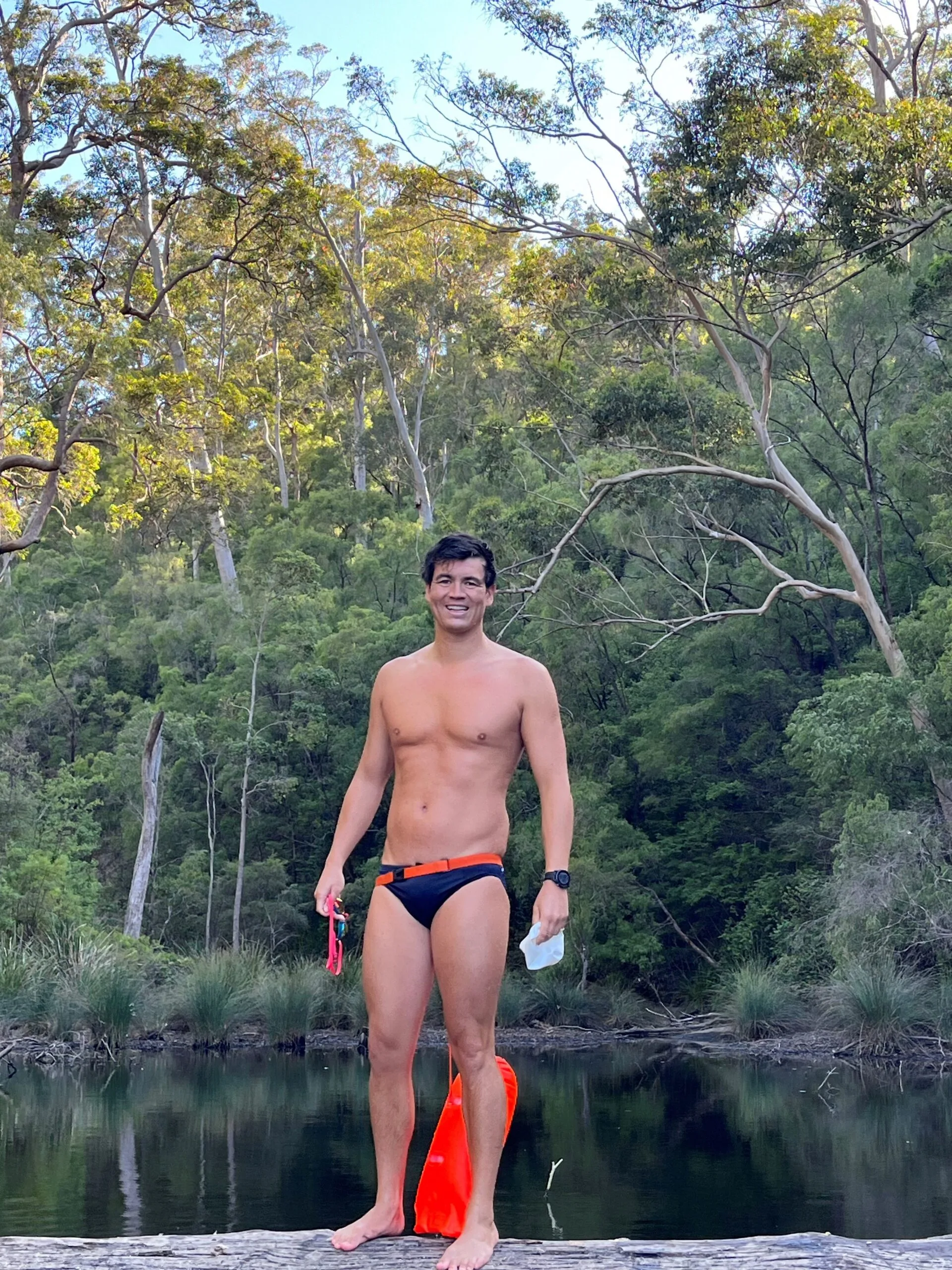 man in speedos beside lake