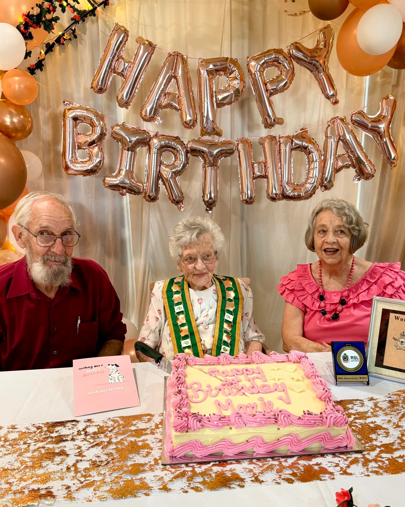 woman with daughter, son-in-law and huge birthday cake that reads 'happy birthday marie'