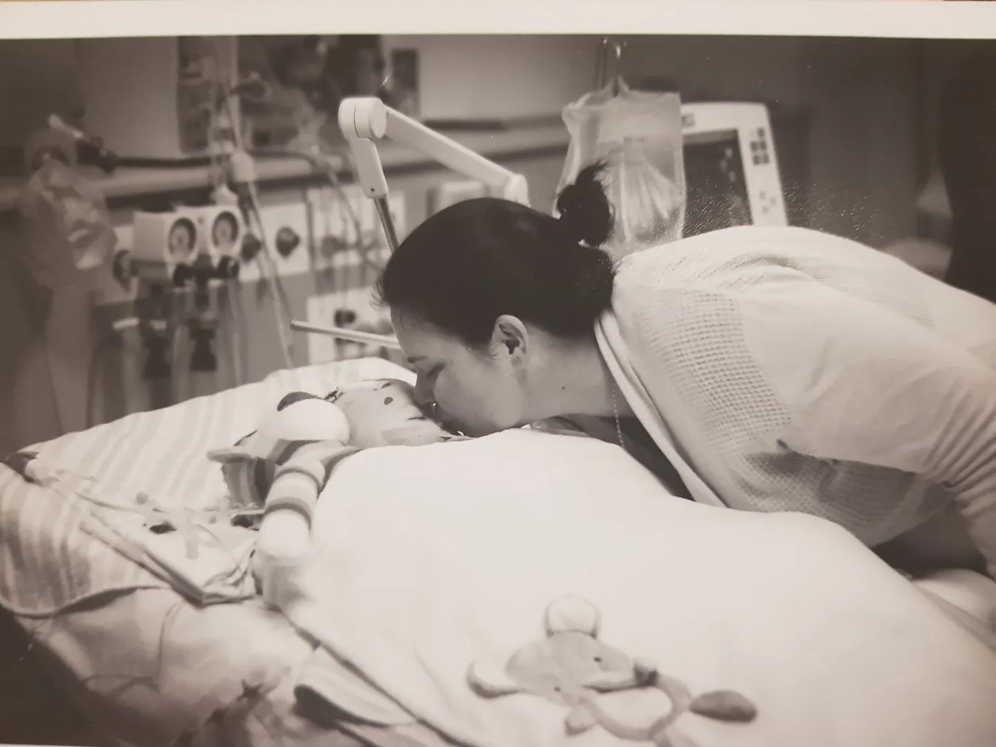 black and white photo of mum kissing baby