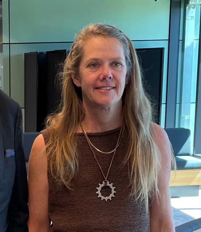 woman wearing brown shirt with cog necklace 