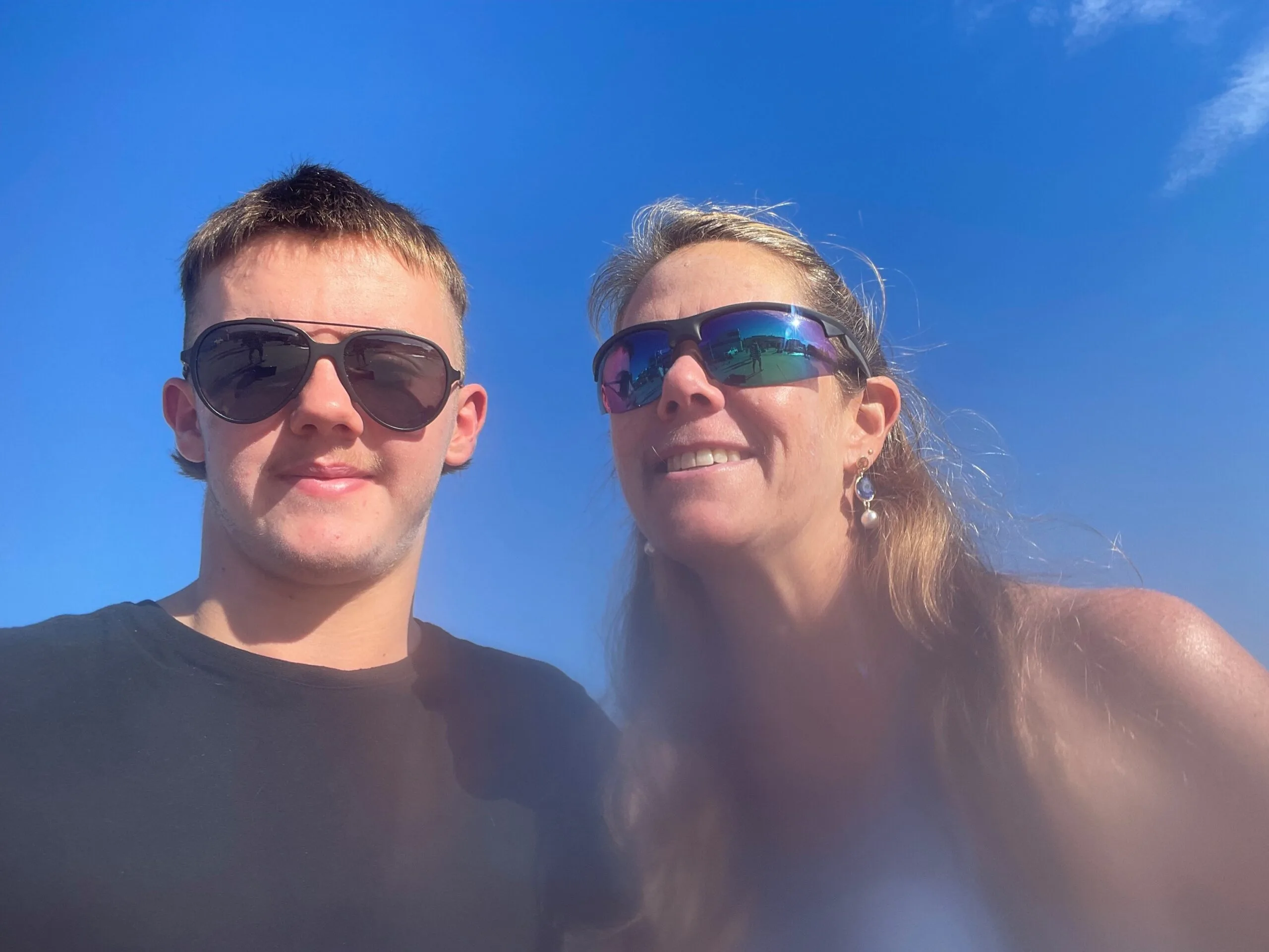 mother and son wearing sunglasses sky is blue behind them
