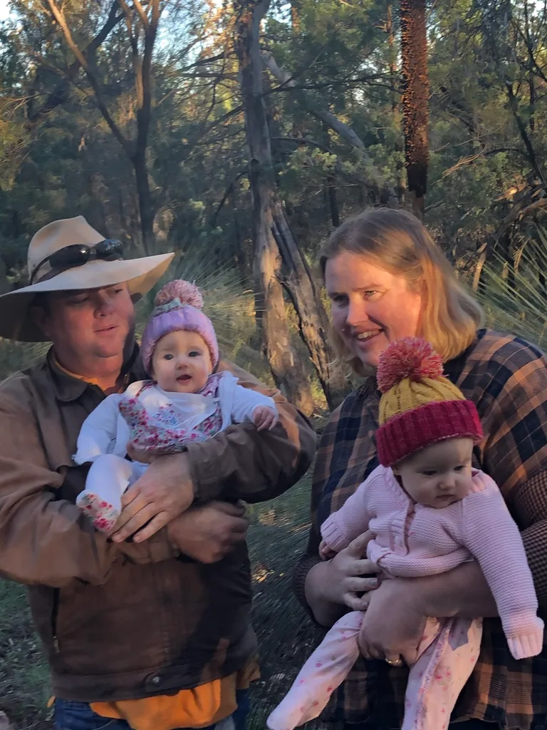 man in hat holding baby and woman holding baby in hat