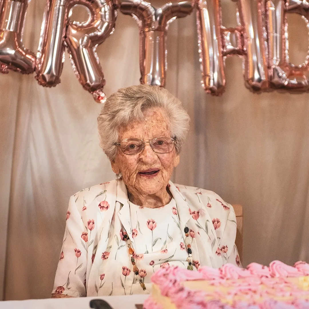 woman in flower blouse with pink cake