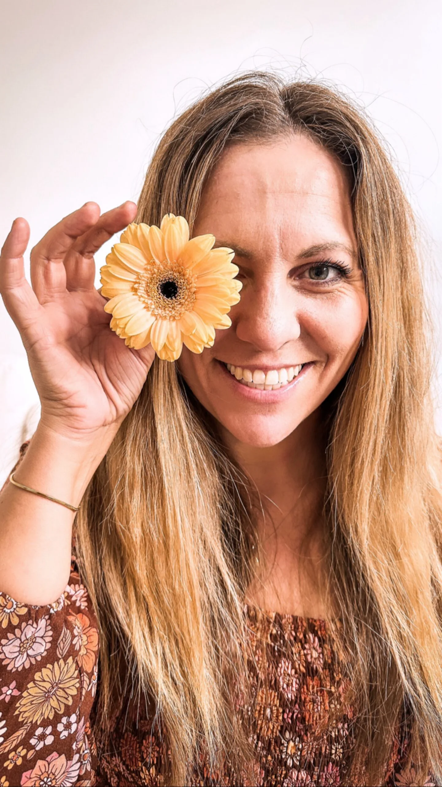 woman taking selfie holdng flower to her eye
