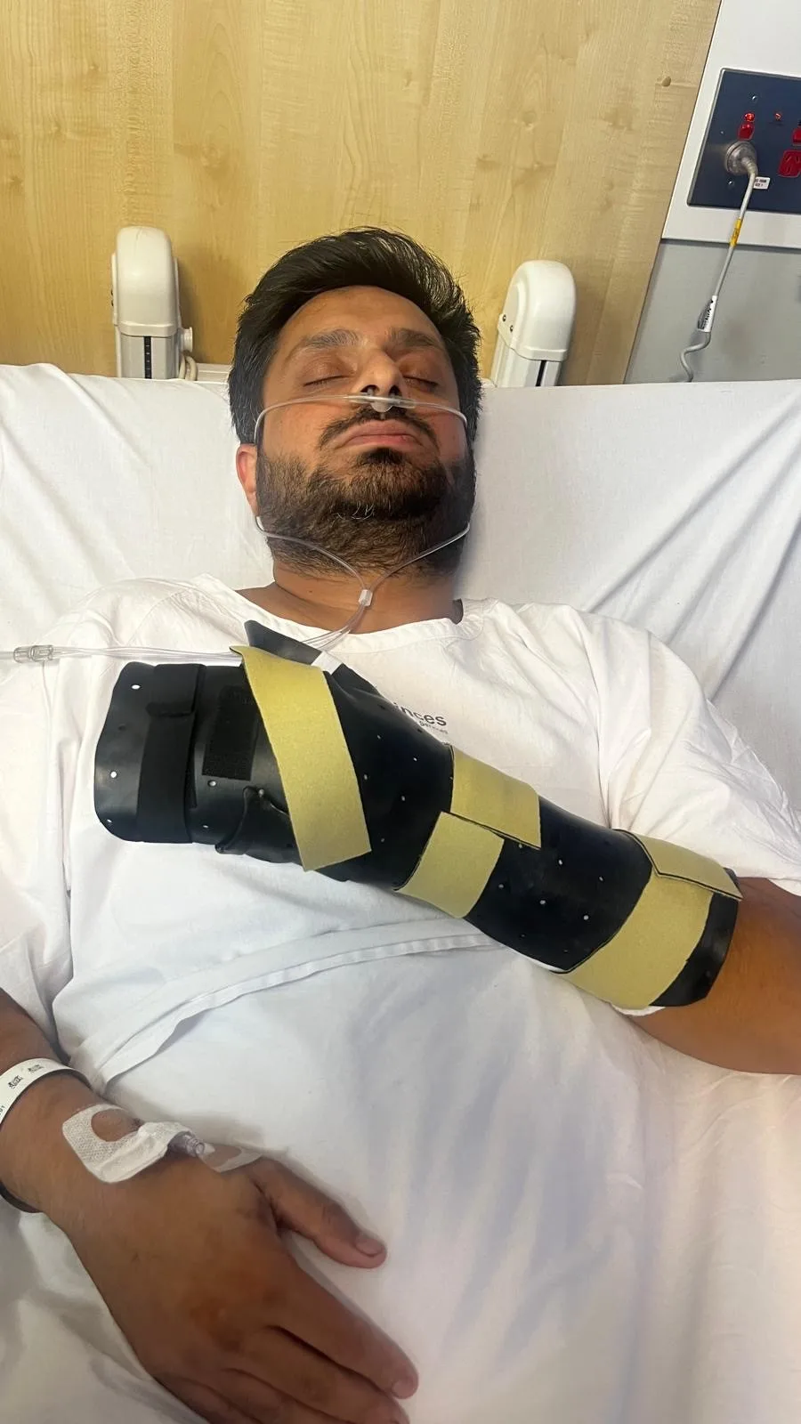 Man sleeping in hospital bed with arm in slingshot resting on the chest.