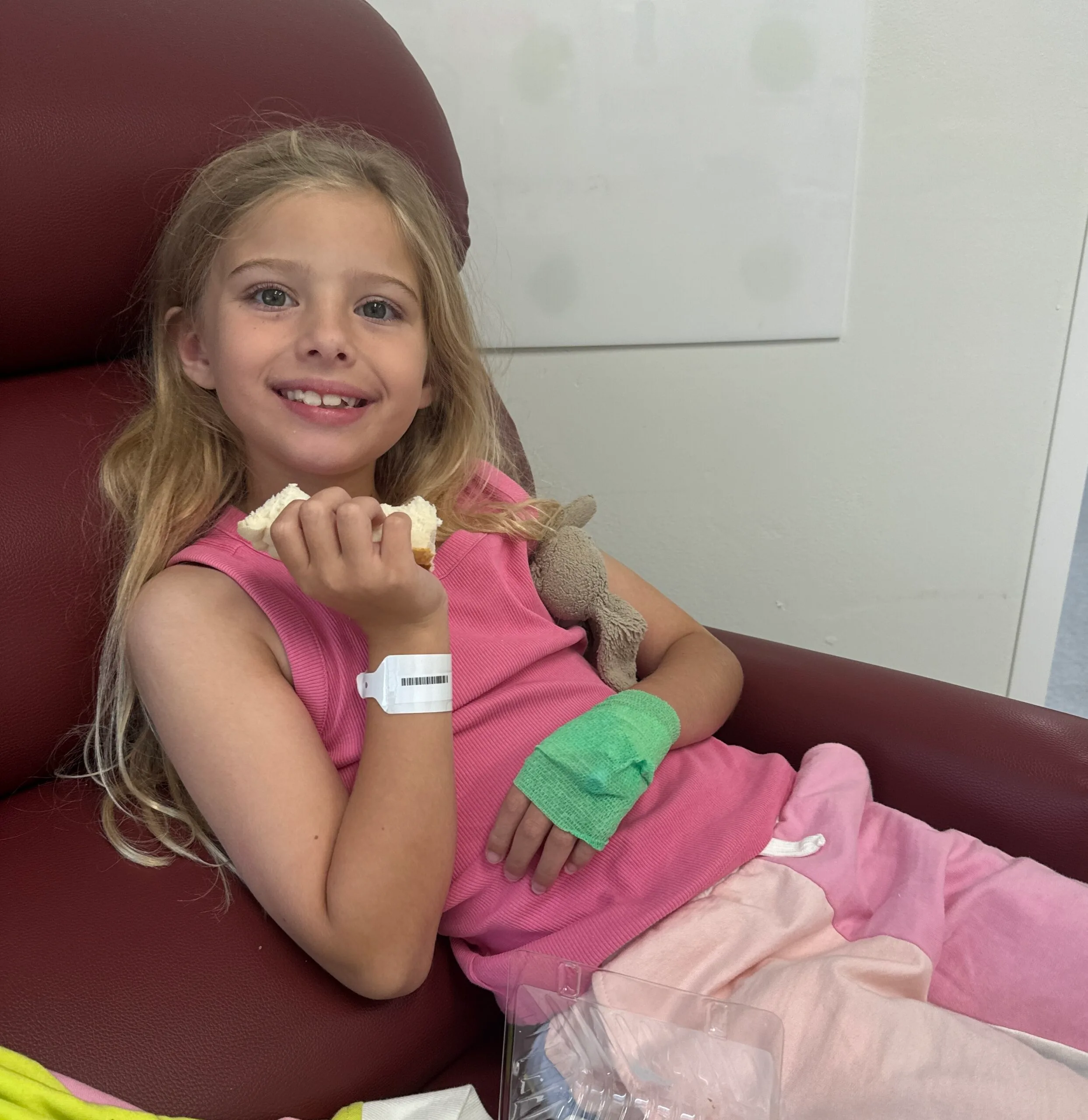 girl with hospital bracelet on in pink top and pants