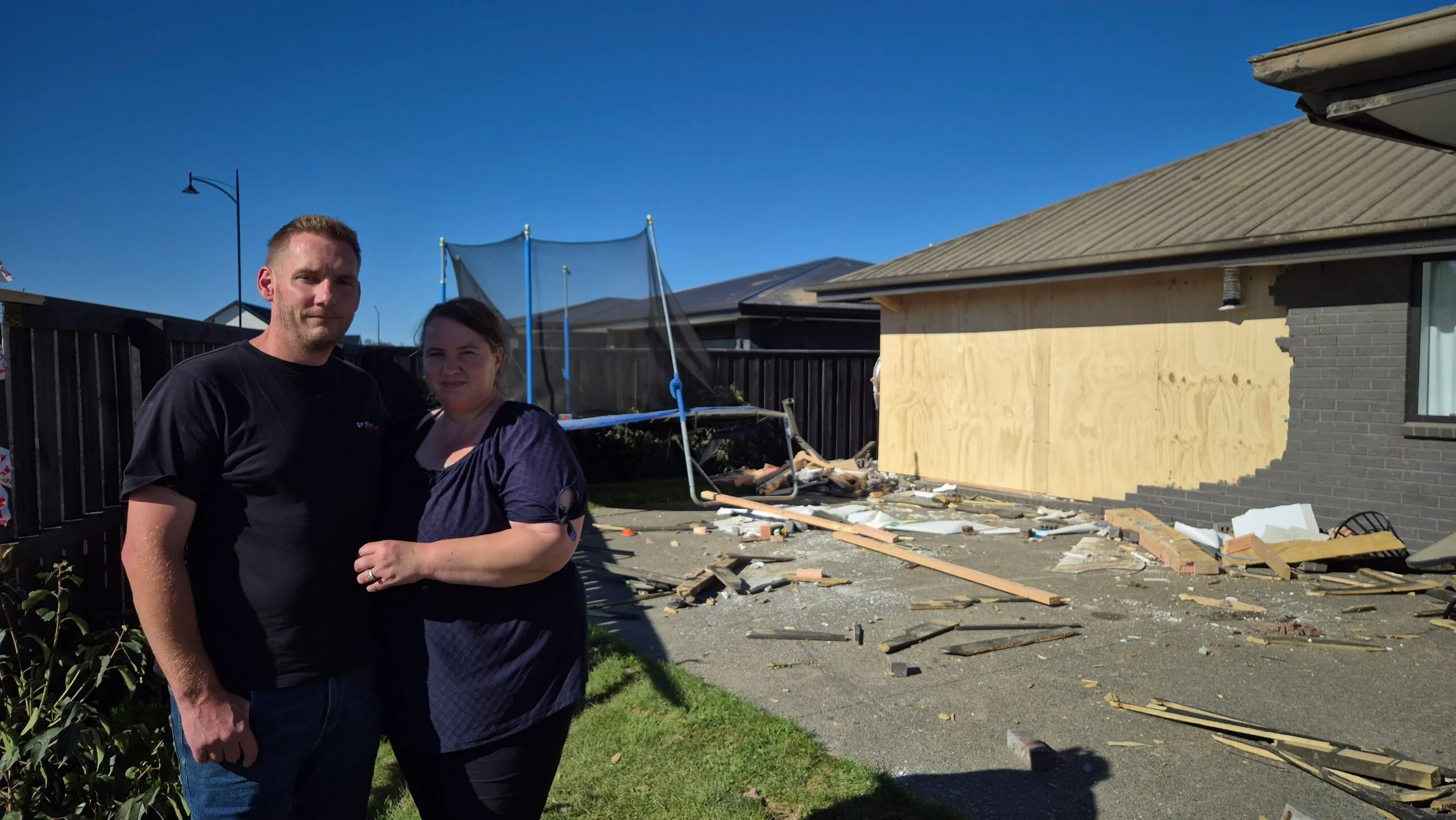man and woman in front of destroyed house