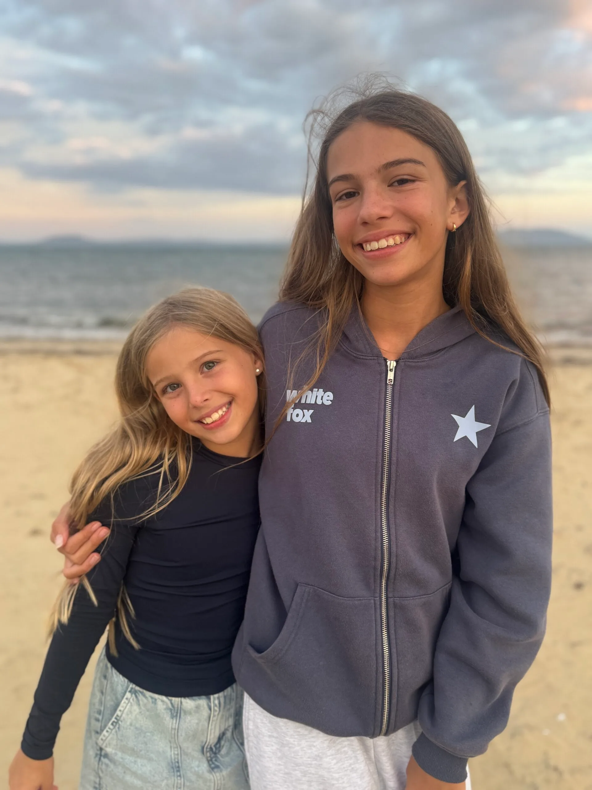 sisters cuddling at the beach